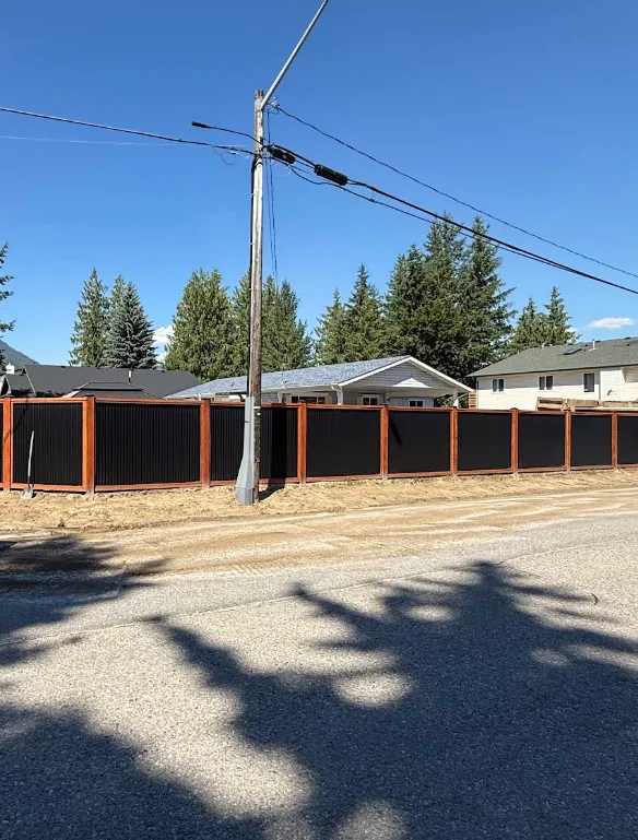 Black metal panel fence with stained-wood frame across a residential property