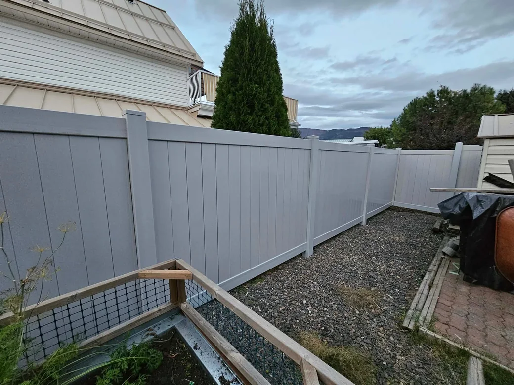 Grey vinyl privacy fence along a backyard