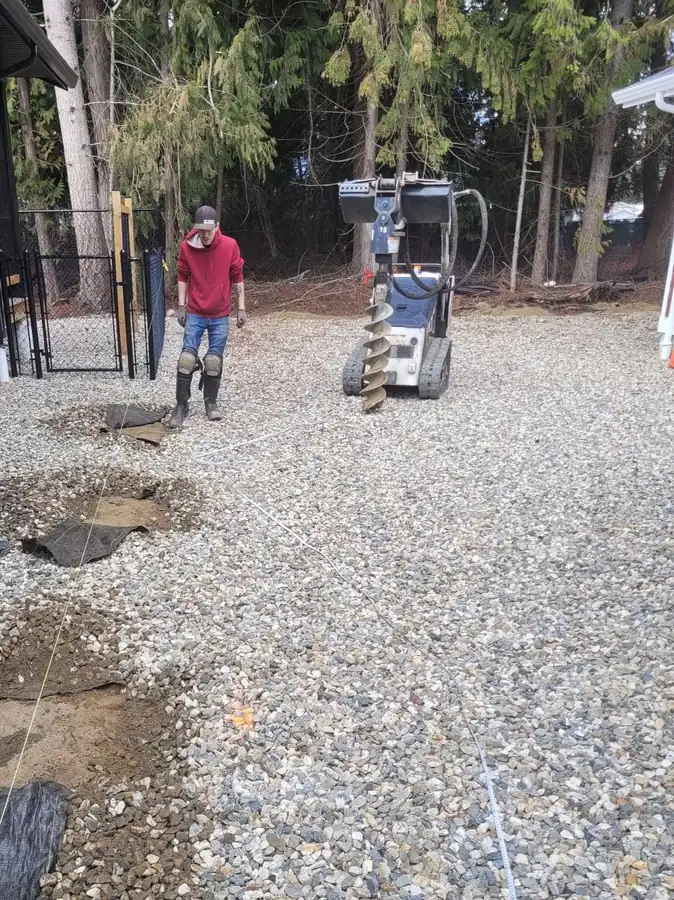 Auger drilling post holes on a fence line