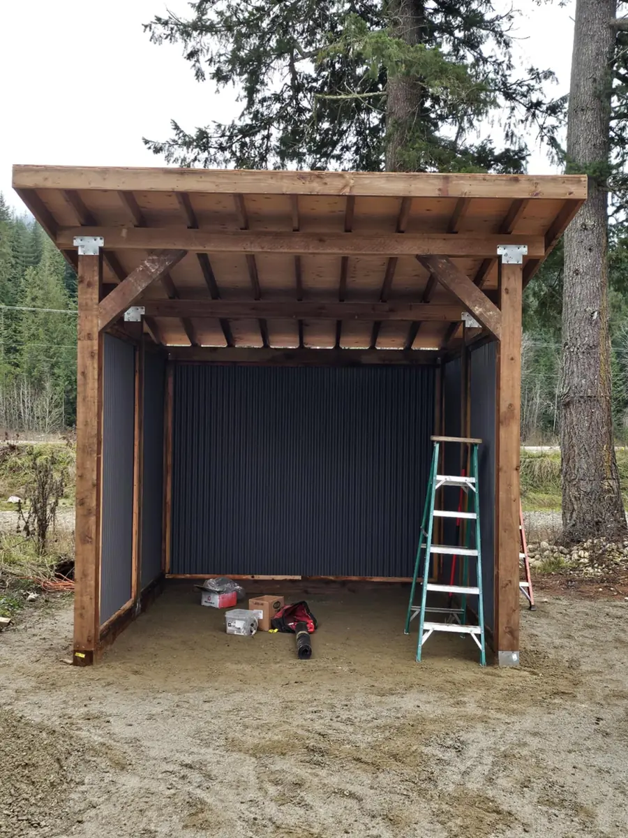 Timber-framed covered structure with cedar posts and dark metal walls
